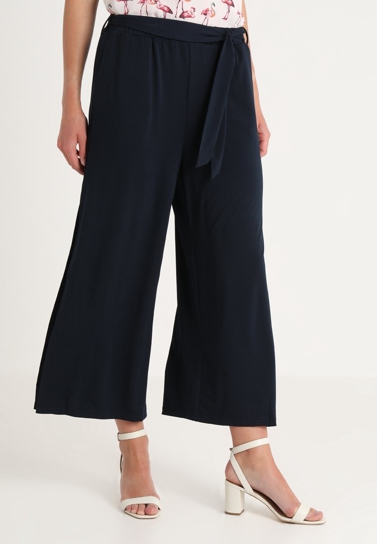 Pantalon large marine avec taille à nouer, en tissu doux. Dispose d'ouvertures sur les côtés pour plus de liberté de mouvement.