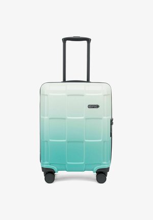 Valise rigide avec un dégradé de turquoise clair à foncé, présentant un motif en carrés texturé, une poignée rétractable et quatre roues noires.