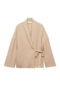 Beigen värinen kietaisupaita teksturoidusta kankaasta, jossa on leveät hihat, vyötäröllä solmittava vyö ja huivikaulus.