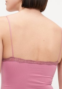 Débardeur rose à fines bretelles, orné d'une délicate bordure en dentelle le long de l'encolure, fabriqué en tissu doux et extensible.
