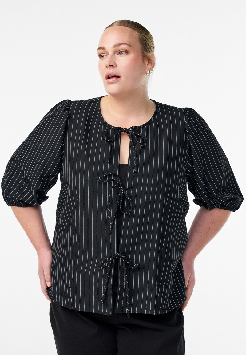 Črna prugasta bluzica s kratkimi napihnjenimi rokavi, ki ima okroglo ovratnico in sprednje zapiranje na zavezo. Narejena je iz lahkotnega blaga z gladko teksturo.