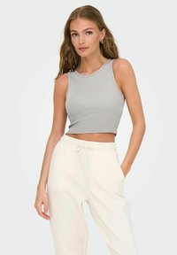 Grå ærmeløs crop top med rund hals og ribbet tekstur. Sammen med hvide sweatpants med elastisk talje og lommer.