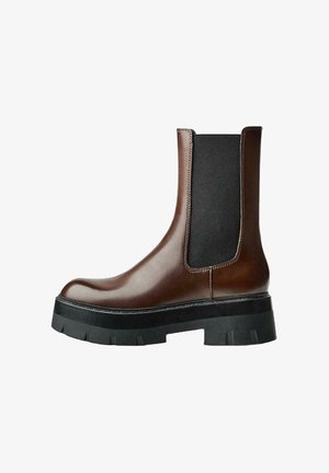 Hnědé kožené Chelsea boty s elastickými postranními panely, robustní černou gumovou podrážkou a minimálními švy, které mají elegantní siluetu.