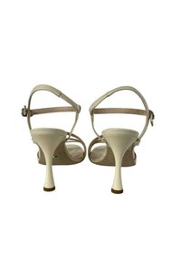 Sandali beige con tacco alto, cinturini sottili alla caviglia, tacco aperto, punta affusolata e un tacco distintivo scolpito. Texture liscia in tutto.