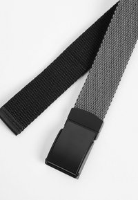 Ceinture tissée avec une palette de couleurs noire et grise, dotée d'une finition texturée. Elle possède une boucle en métal noir mat pour un maintien sécurisé.