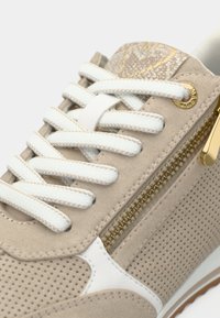 Μπεζ σουέντ αθλητικό παπούτσι με λευκή διάτρητη πλευρά, λευκά κορδόνια, χρυσές λεπτομέρειες και πλευρικό φερμουάρ. Υφή επιφάνειας με λεία σόλα.