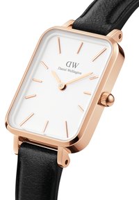 Rose gold rectangular watch with a white dial, black leather strap, raised hour markers, and a crown on the side.