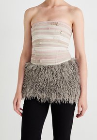 Trägerloses Oberteil aus einem strukturierten, beige-rosa Stoff mit horizontalen Streifen und Verschlüssen, verziert mit einem flauschigen grauen Pelzsaum.