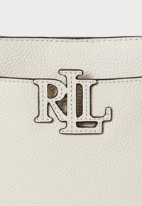 Λευκή τσάντα από υφή δέρματος με έντονη μαύρη και λευκή λεπτομέρεια του λογότυπου RL. Διαθέτει αντίθετη ραφή και λείες άκρες.