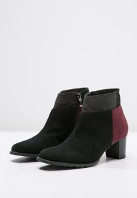 Stivaletti neri in suede con tacco a blocco, dotati di una parte superiore grigia scura e un pannello laterale bordeaux; chiusura con zip sul lato esterno.