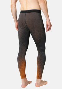 Black and orange gradient athletic leggings with textured pattern, elastic waistband, form-fitting design, and smooth fabric, suitable for exercise.