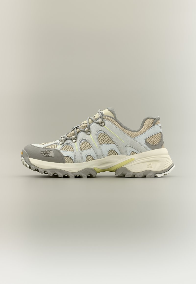Ανοιχτό γκρι και μπεζ παπούτσι για τρέξιμο σε μονοπάτια με δίχτυνα πάνελ, ανθεκτική σόλα και κορδόνια, με λογότυπο The North Face στο μπροστινό μέρος.