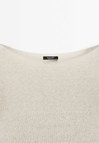 Jasno beżowy sweter o miękkiej fakturze, szerokim dekolcie i metce z napisem "Massimo Dutti". Materiał wydaje się dzianinowy i lekki.