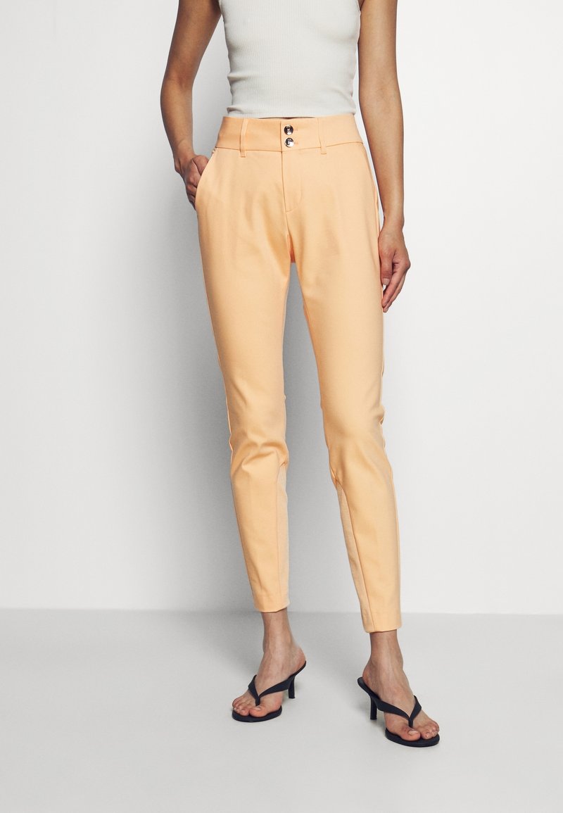 Peach-colored tailored pants with a slim fit, featuring two front pockets and two decorative buttons at the high waist. Smooth texture.