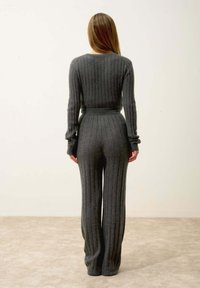 Šedý žebrovaný pletený dvoudílný outfit obsahující uzoučký top a široké kalhoty, vyrobený z texturované látky, s dlouhými rukávy a páskem na úpravu v pase.