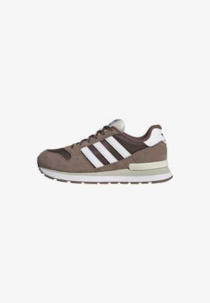Brauner und weißer Adidas-Sneaker mit Obermaterial aus Wildleder und Mesh, weißen drei Streifen, gepolsterter Sohle und Schnürverschluss, seitlich dargestellt.