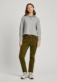 Grå cropped hettegenser med justerbar snor, kombinert med olivengrønne bukser og lyse sporty sko. Enkelt design uten mønstre.