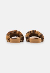 Faux fur slide sandals with a brown and black leopard pattern, featuring a soft upper and a wooden sole. Rounded design with a cozy texture.
