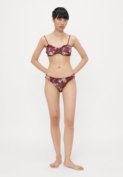Bordo krāsas bikini komplekts ar ziedu rakstiem. Topam ir ruffles apmale un regulējamas siksnas; apakšdaļai ir dekoratīvi sānu akcenti.