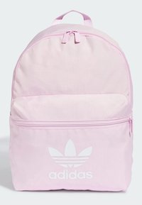 Roze tkaninski ruksak s dvostrukim patentnim zatvaračem, prednjim džepom i velikim bijelim Adidas logom. Zaobljeni vrh i čvrsta ručka za nošenje.