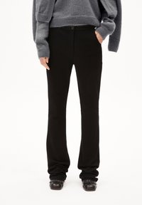 Černé rozšířené kalhoty z měkkého materiálu, s dvojitým zapínáním, předními kapsami a vypasovaným střihem kolem pasu a stehen.