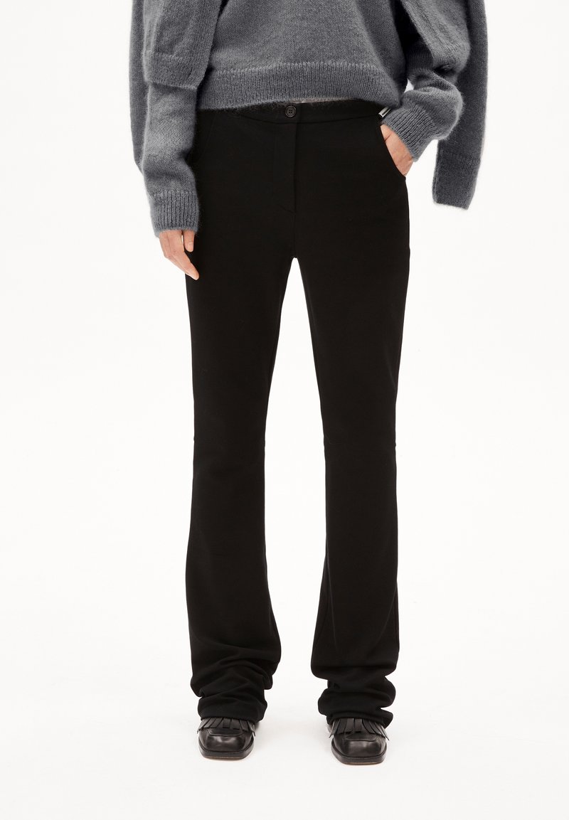 Černé rozšířené kalhoty z měkkého materiálu, s dvojitým zapínáním, předními kapsami a vypasovaným střihem kolem pasu a stehen.