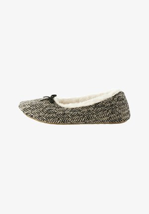 Chausson à motif en chevrons noir et beige, avec une doublure douce et pelucheuse et un petit nœud noir en accent à l'avant. Semelle plate.