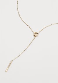 Gold-toned chain necklace with bar links, circular pendant, and a vertical pendant adorned with small clear gemstones.