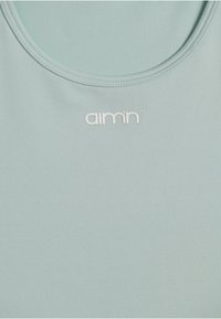Ljusblå sportstopp med en slät textur, rundad halsringning och en liten vit logotyp "aimn" tryckt på bröstområdet.