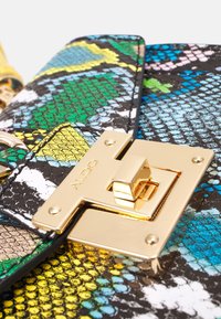 Torebka w wielokolorowy wzór wężowej skóry, z indywidualnym złotym zapięciem, w kształcie trójkąta, z teksturowaną powierzchnią i dekoracyjnymi akcentami.