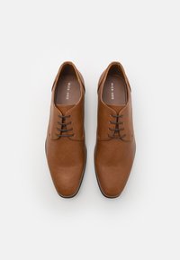 Brown leather lace-up shoes with a smooth texture, rounded toe, five eyelets, and contrasting black sole. "PIER ONE" logo inside.