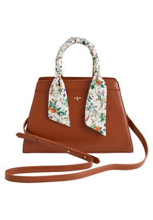 Sac à main en cuir marron avec des poignées enveloppées de tissu à imprimé floral et une longue bandoulière réglable, orné d'un petit emblème d'abeille en or.