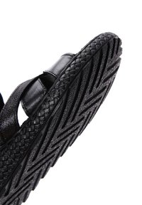 Sandalo nero con suola intrecciata e fondo texturizzato e decorato. La parte superiore presenta fasce eleganti e una finitura liscia.
