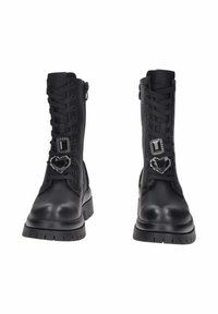 Stivali da combattimento neri in pelle con suole spesse, lacci frontali, cerniere laterali e spille decorative a forma di cuore e rettangolo gioiello nero sui lacci.
