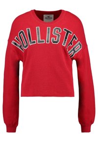 Felpa rossa cropped in cotone, con maniche lunghe e scollatura rotonda, con la scritta "HOLLISTER" stampata in lettere grasse sul davanti.