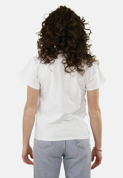 T-shirt bianco in cotone con maniche corte, scollatura rotonda e vestibilità rilassata, abbinato a jeans in denim azzurri.