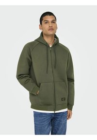 Olivgrön zip-up hoodie med dragsko i huvan, raglanärmar, framfickor och en logopatch på sidan. Mjuk bomullsblandning.