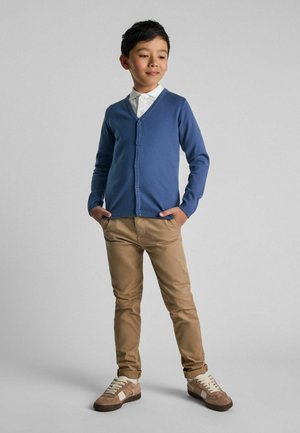 Blauer cardigan mit V-Ausschnitt, Knopfverschluss und langen Ärmeln, kombiniert mit khakifarbigen Chinos und beigen Sneakers. Glatter Stoff, taillierte Passform.