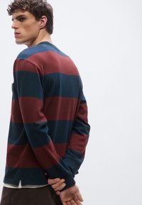 Μακρυμάνικο ριγέ πουκάμισο σε ναυτικό μπλε και μπορντό με στρογγυλή λαιμόκοψη. Διαθέτει ίσια γραμμή και πλαϊνές σχισμές στο τελείωμα για επιπλέον άνεση.