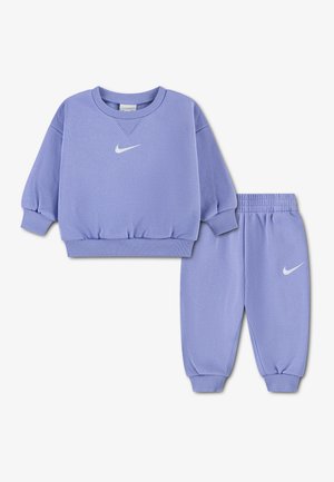 Ensemble sweat-shirt et pantalon de survêtement enfant couleur lavande avec poignets côtelés et logos Nike sur la poitrine et la jambe.