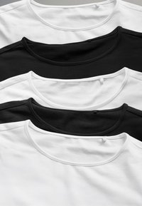 Drie T-shirts in een gestapelde opstelling: één wit, twee zwarte, met een ronde halslijn en glad katoenmateriaal.