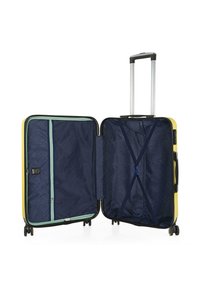 Maleta rígida amarilla con un interior azul marino, cuenta con un bolsillo de malla con cremallera, correas cruzadas ajustables y un asa retráctil.