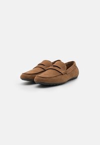 Brown suede loafers with a rounded toe, featuring a raised seam detail across the upper and textured rubber sole for grip.