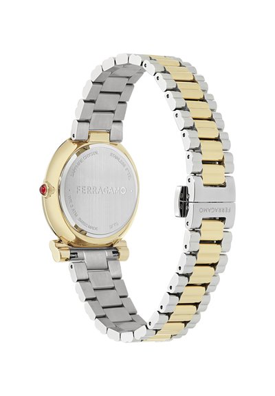 Reloj de pulsera de acero inoxidable en plata y oro con una caja redonda dorada, acento rojo y una pulsera enlazada que presenta tonos de metal alternos y una textura suave.