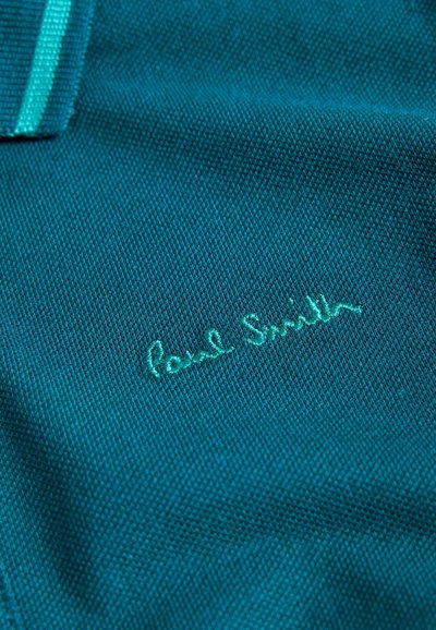 Zöldkék szövet texturált mintázattal; az alján halványkék hímzett felirat olvasható: "Paul Smith".
