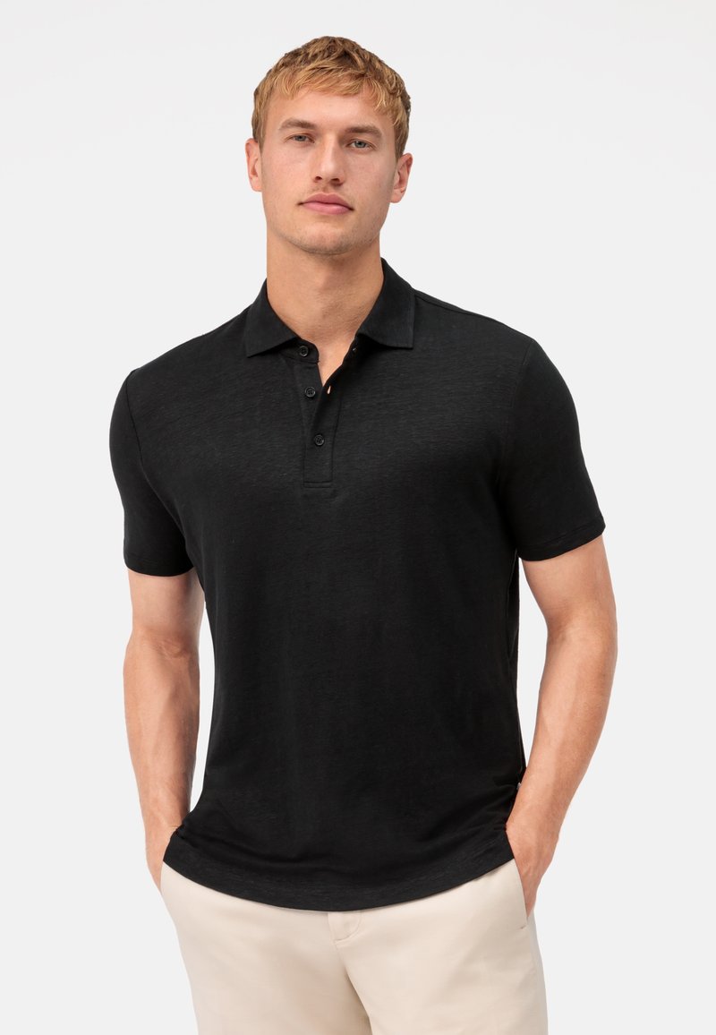 Schwarzes Polo-Shirt mit kurzen Ärmeln aus leichtem, strukturiertem Stoff, mit einer Knopfleiste und einem klassischen Kragen. Taillierte Passform.