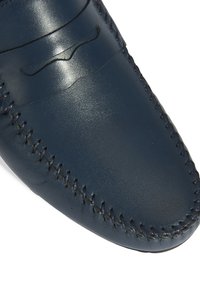 Marine leren instapper met handgestikte details, een gladde textuur en een ronde neus met een subtiel golfpatroon op de bovenkant.