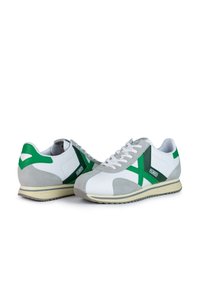 Zapatillas blancas y grises con acentos verdes. Presentan una mezcla de materiales de cuero y ante, punta redondeada, diseño de cordones y suela texturizada.
