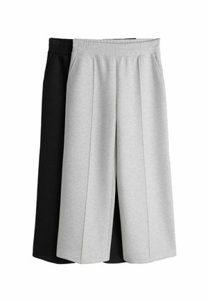 Dva páry rozšírených skrátených teplákov, jeden svetlosivý a jeden čierny, oba s elastickými pásmi a bočnými vreckami.