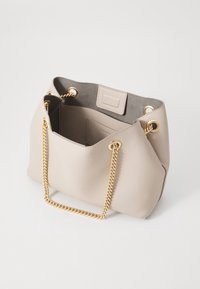 Borsa a mano in pelle beige con superficie texturizzata, manici a catena dorata e interno grigio. Presenta una chiusura a gancio e un'etichetta rettangolare.